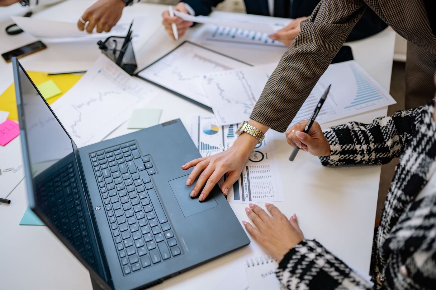 Equipe reunida analisando gráficos e relatórios em torno de um notebook